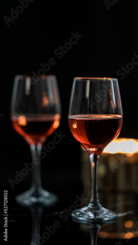 two glasses of red wine on a black table. Candle in the background