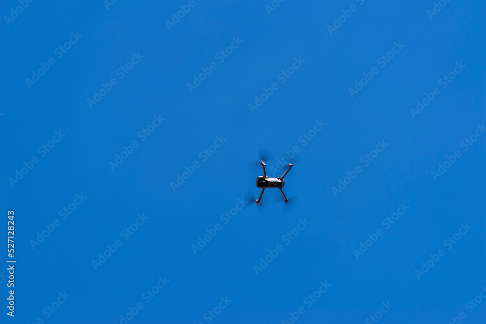 Latający dron ( kwadrokopter , Quadrocopter ) z kamerą na tle błękitnego nieba .