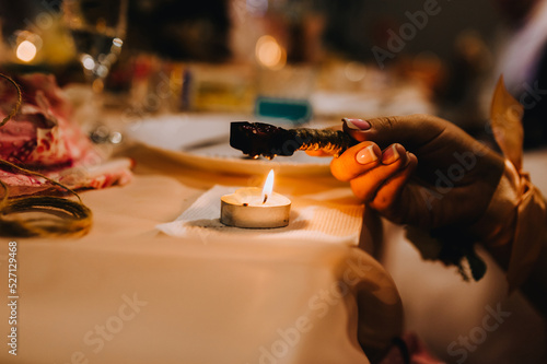 The girl performs the ceremony, the ritual holding melted wax in her hands over a burning candle in the form of a heart in the dark Fototapet