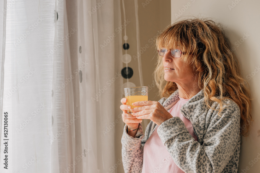 middle-aged woman at home drinking orange juice middle-aged woman at home drinking orange juice