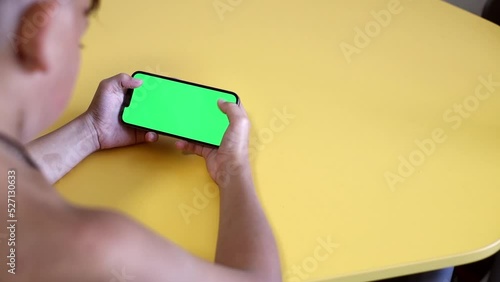 Chroma key mock-up on smartphone in hand. teenage boy use phone with green screen layout, color key, Watch content, play game. Use green screen for copy space closeup. Slow motion.