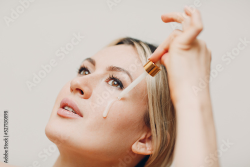Tableau sur toile Cosmetic oil royal jelly applying with pipette on face of young woman