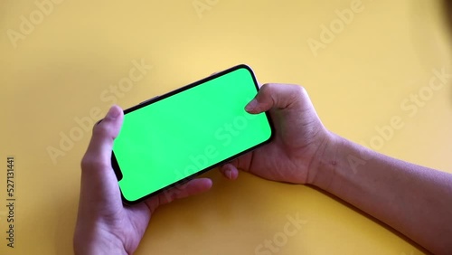 green screen. The child is holding a Smartphone in hand Close-up playing a game. phone with blank green screen mock up display for advertising. Slow motion.