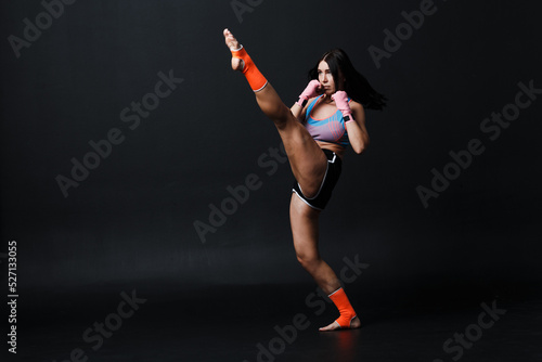 Sportsman muay thai woman boxer posing in training studio photo