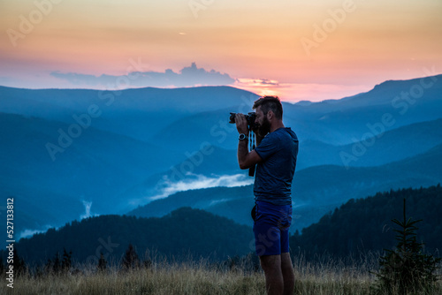 man taking photos of sunset in mountains © Melinda Nagy
