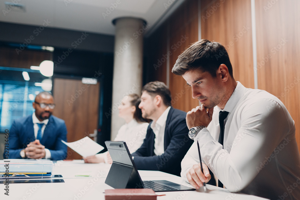 Businessman using working with laptop sits at table at office meeting. Business people man and woman group conference discussion Businessman using working with laptop sits at table at office meeting. Business people man and woman group conference discussion