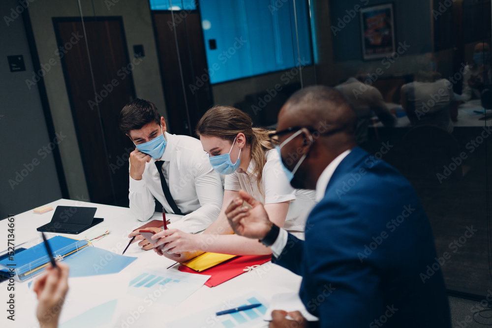 Fototapeta premium Businessman and businesswoman team in medical face mask at office meeting. Business people group conference discussion with boss.