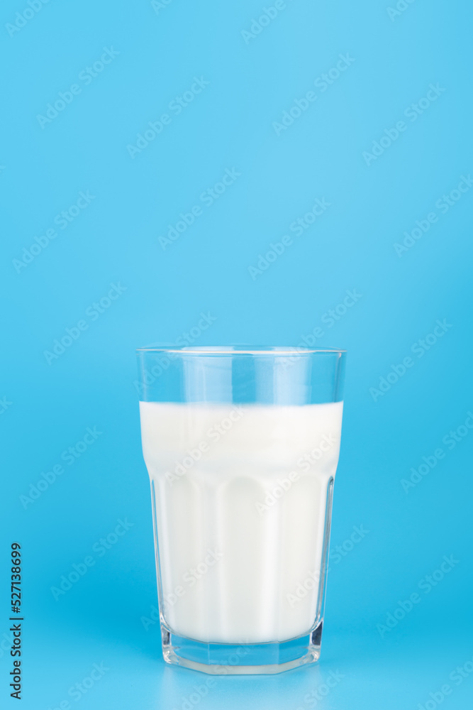 close-up view of white milk in transparent faceted glass. on blue background, side view. Dairy product concept, copy space. close-up view of white milk in transparent faceted glass. on blue background, side view. Dairy product concept, copy space.