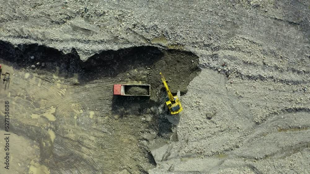 Top-Down View . An Industrial Excavator On An Open Road Section Loads Rock And Earth On A Very Large Dump Truck, A Bulldozer Rakes The Earth .The Excavator Is Working .Unmanned Image Of A Construction Top-Down View . An Industrial Excavator On An Open Road Section Loads Rock And Earth On A Very Large Dump Truck, A Bulldozer Rakes The Earth .The Excavator Is Working .Unmanned Image Of A Construction