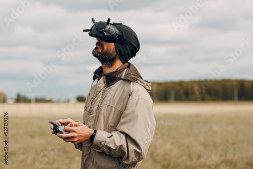 Man controlling fpv quadcopter drone for aerial photography and videography with goggles antenna remote controller. photo