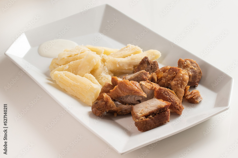 pork rinds with steamed root and sour milk cream served on a white dish