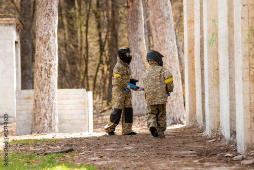 several children with machine guns and paintball masks play war
