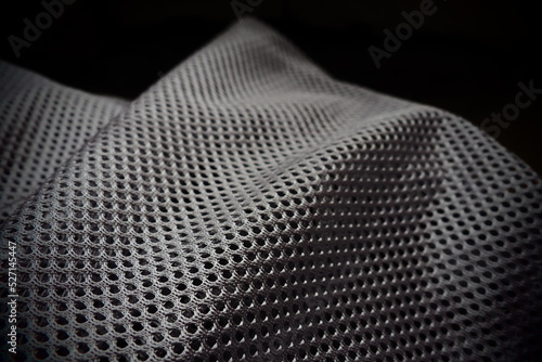 Synthetic fabric with holes laid in waves. Beautiful drape. Fabric for curtains, interior design, and decor. Wrinkled gray fabric.
