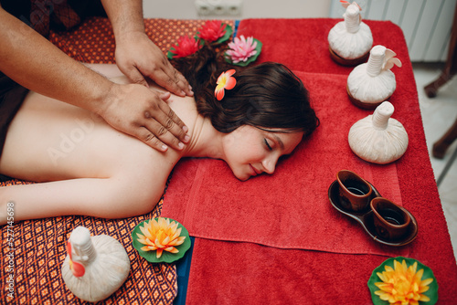 Thai man making classical thai massage procedure to young woman at beauty spa salon