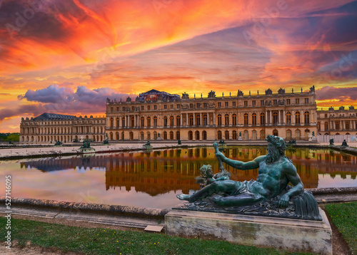 The Palace of Versailles, just outside of Paris, France, is seen from the backyard gardens during a beautiful colourful sunset. photo