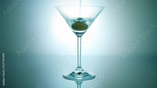 Martini alcohol drink cocktail pouring into the glass gobled with olive photo