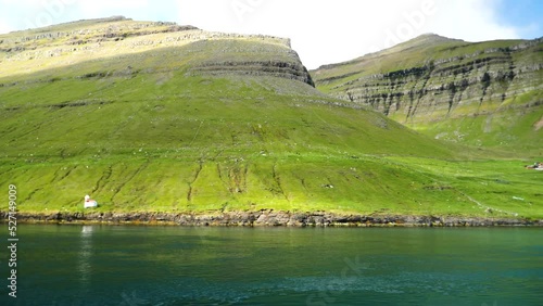 Ferry arriving to the port in Sydradalur. Amazing Faroese nature, green hills and beautiful rocky mountains. View to a Kalsoy Island. Sunny day in summer. Movie Island in Faroe Islands. 4k footage photo