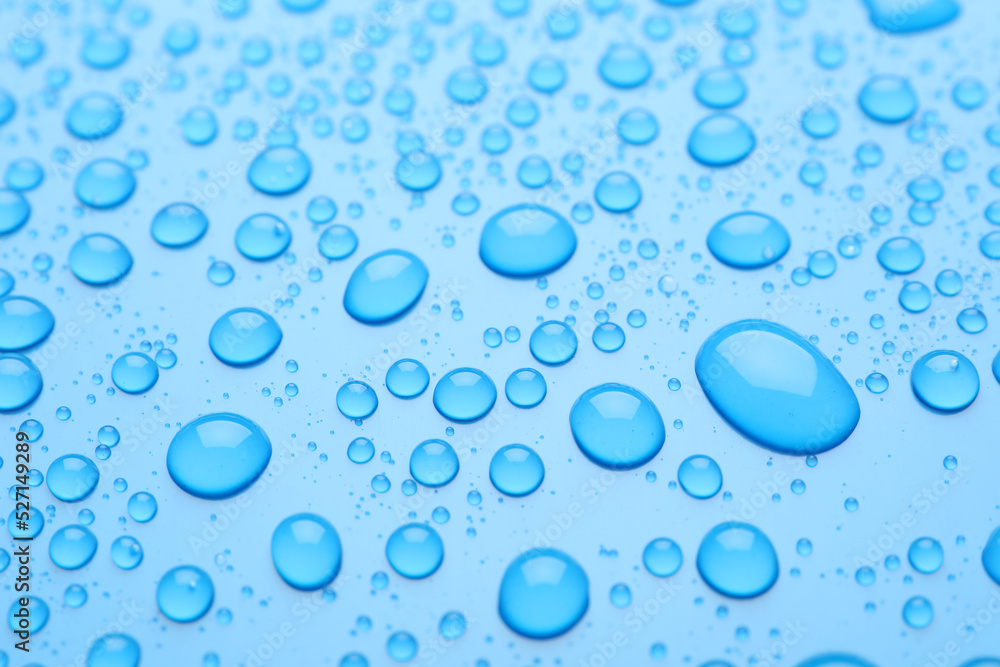 Water drops on light blue background, closeup view
