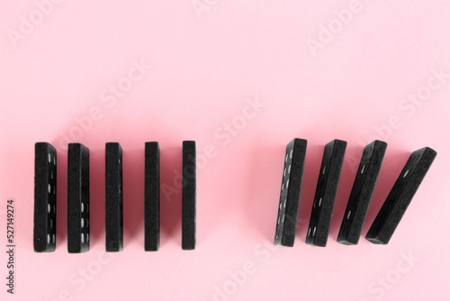 Black domino tiles on pink background, flat lay. Space for text