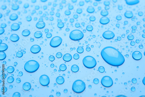 Water drops on light blue background, closeup view