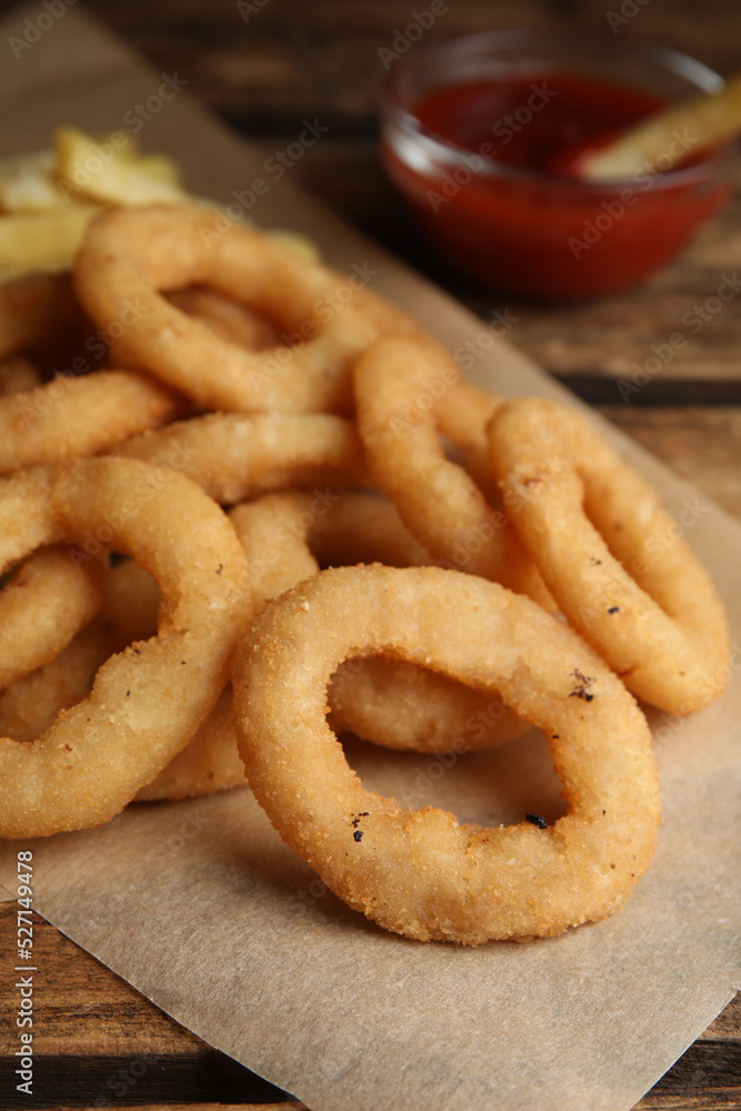 Delicious onion rings, fries and ketchup on wooden table, closeup Delicious onion rings, fries and ketchup on wooden table, closeup