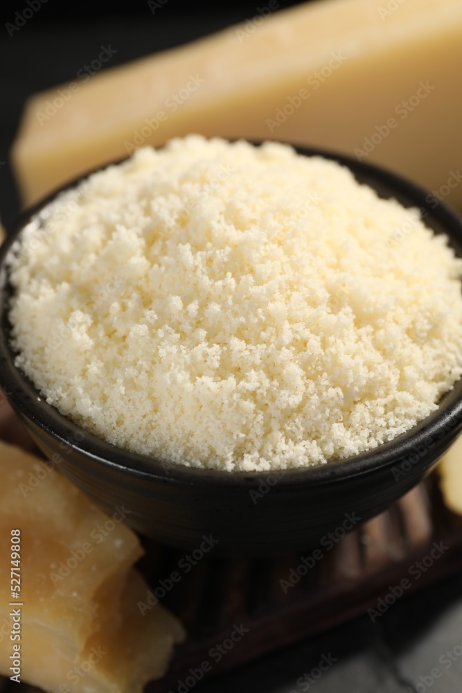 Bowl with grated parmesan cheese on table, closeup Bowl with grated parmesan cheese on table, closeup
