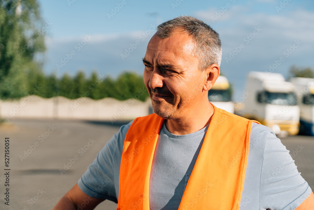 Fototapeta premium Portrait of caucasian mature man on semi-truck vehicles parking background. Truck driver worker 