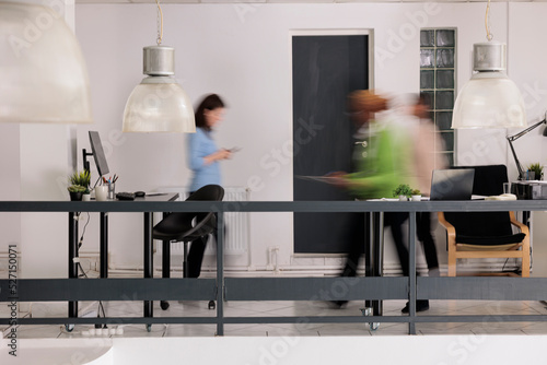 Canvas Print Diverse employees silhouettes walking in business coworking space, long exposure effect