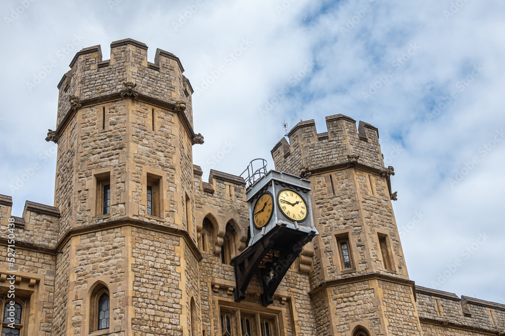 London, England, UK - July 6, 2022: Tower of London. Clock between 2 brown-beige stone lookout towers at center of Waterloo Block building under blue cloudscape London, England, UK - July 6, 2022: Tower of London. Clock between 2 brown-beige stone lookout towers at center of Waterloo Block building under blue cloudscape