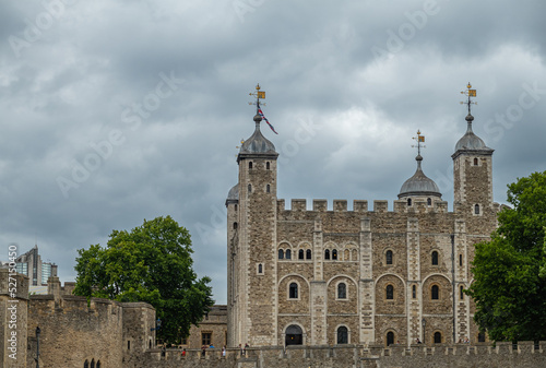 London, England, UK - July 6, 2022: Tower of London. White tower palace building seen over ramparts from Thames River under gray cloudscape.