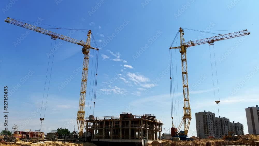 Two tower cranes at a time lapse construction site. Building a concrete multi-story modern residential skyscraper. Construction work at summer day. Two tower cranes at a time lapse construction site. Building a concrete multi-story modern residential skyscraper. Construction work at summer day.