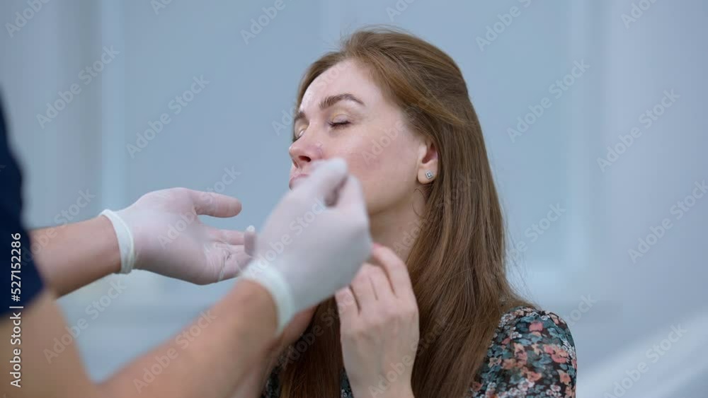 Gorgeous confident brunette woman with green eyes talking with doctor touching face looking up. Portrait of Caucasian patient consulting expert Middle Eastern plastic surgeon indoors Gorgeous confident brunette woman with green eyes talking with doctor touching face looking up. Portrait of Caucasian patient consulting expert Middle Eastern plastic surgeon indoors
