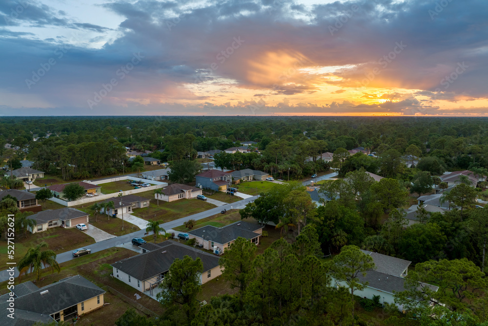 Aerial landscape view of suburban private houses between green palm trees in Florida quiet rural area at sunset Aerial landscape view of suburban private houses between green palm trees in Florida quiet rural area at sunset