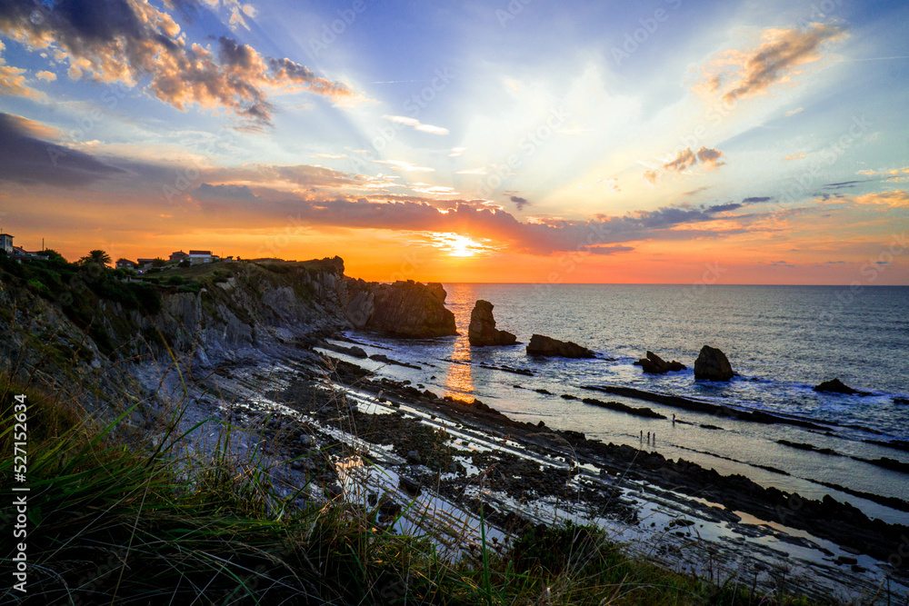 Picture of Beautiful Golden Sunset from Arnia Beach in the Town of Liencres in Cantabria at Sunset with the Dark Blue Sea and Tiny People Strolling by