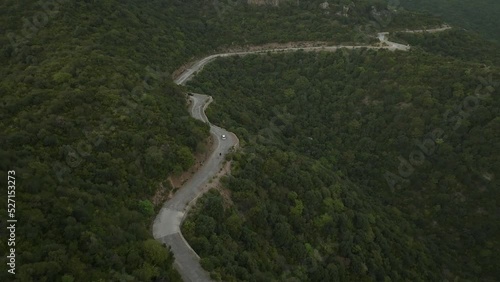 Drone flights in top of a road in the middle of a green forested hill, some cars and people are using the road, filmed in Margalla hills, Islamabad Pakistan, aerial 4 k