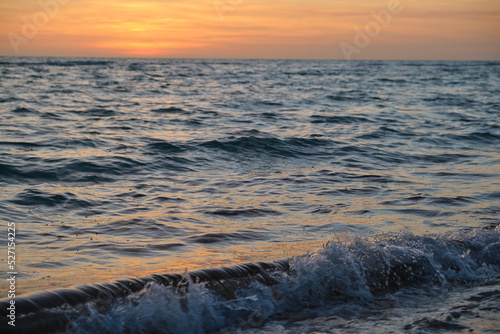 Ocean sunset landscape with soft evening sea water waves crushing on sandy beach