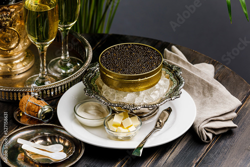 Black caviar on ice in silver bowl and Champagne close-up
