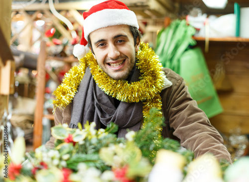 Portrait of happy young man Christmas hat with looking toys at fair outdoor