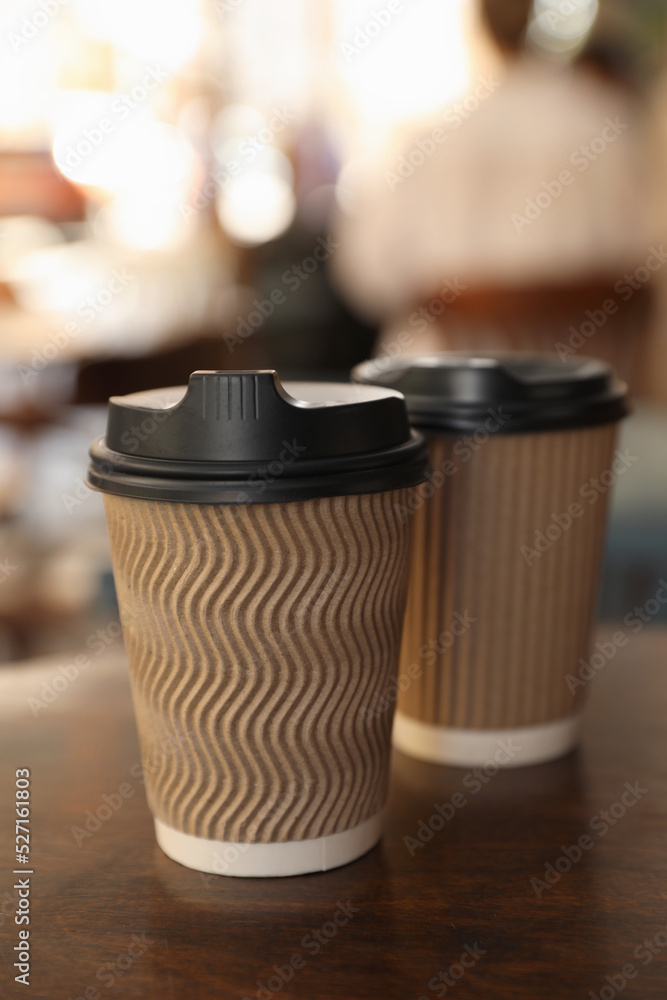 Cardboard takeaway coffee cups with plastic lids on wooden table in city Cardboard takeaway coffee cups with plastic lids on wooden table in city