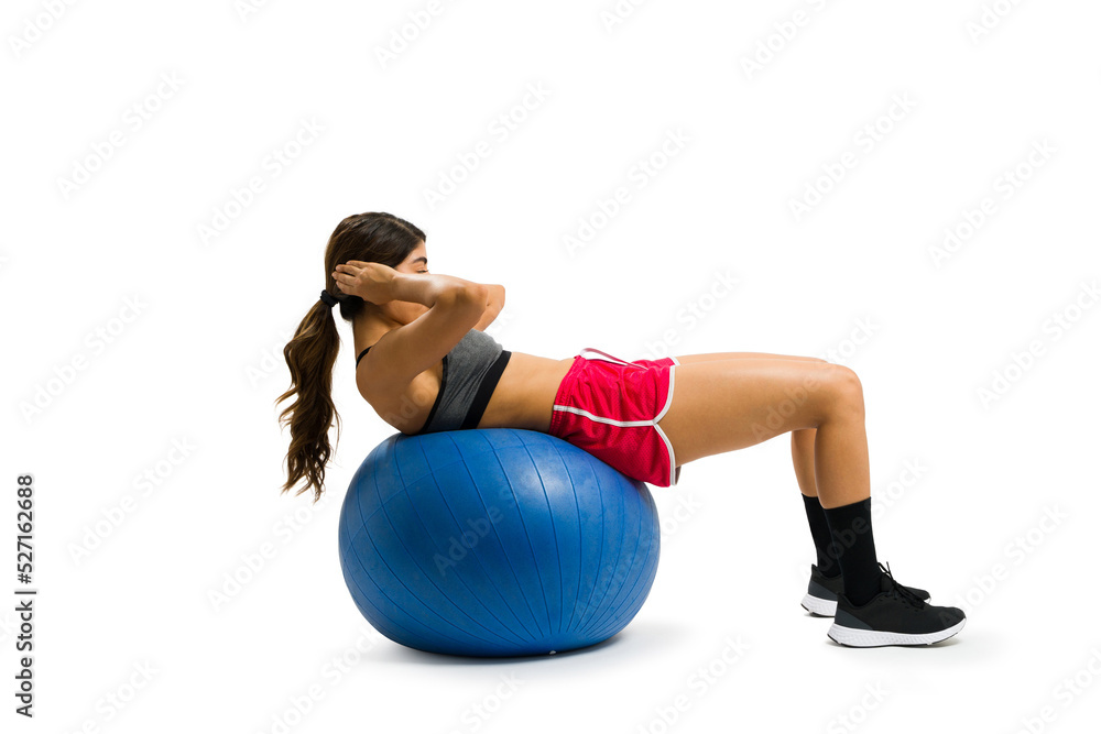 Active woman practicing sit ups on a stability ball during her workout Active woman practicing sit ups on a stability ball during her workout