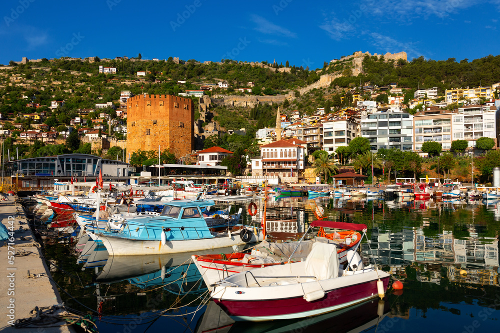 Pier of Alanya with moored boats. View of Kizil Kule (Red Tower) and Castle of Alanya, Antalya Province, Turkey.