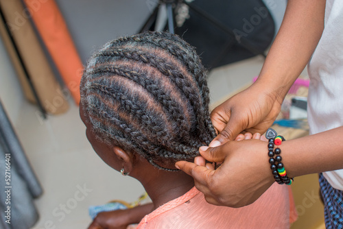 Hands of an hairdresser  stylist or entrepreneur making and weaving the grey hair of an elderly African Nigerian woman