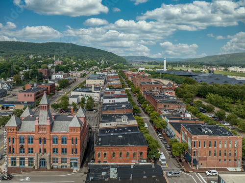Obraz na płótnie Aerial view of Corning Steuben County, New York downtown, Market Street, glass factory, chemung river, centerway walking bridge, little joe tower, parking lot with cloudy blue sky w salonie