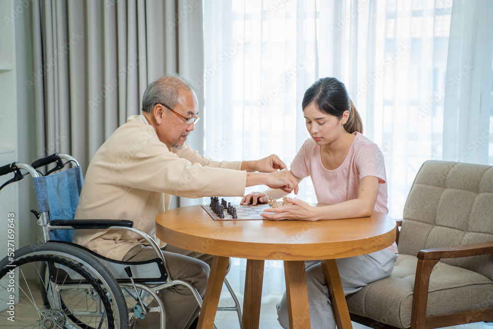 Happy senior man sitting on the wheelchair playing chess together with daughter at home,Playing board games. Happy senior man sitting on the wheelchair playing chess together with daughter at home,Playing board games.