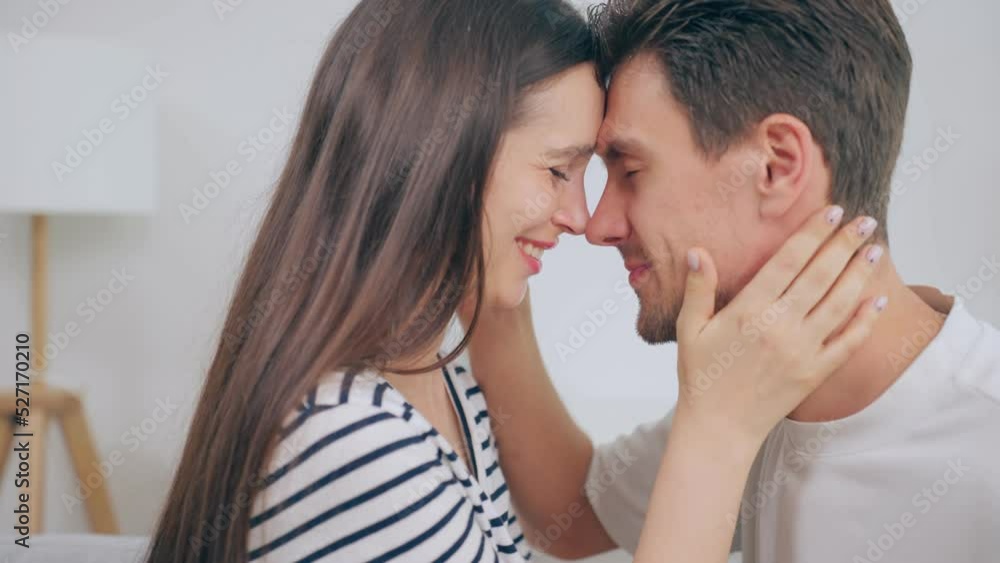 Caucasian young man and woman kissing each other in living room at home Caucasian young man and woman kissing each other in living room at home