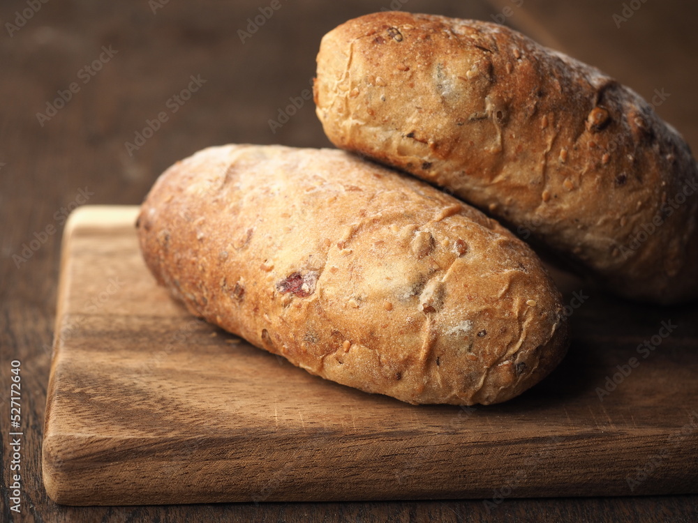 Whole wheat bread with mix cereal seed and dried fruit in oblong loaf shape on wood Whole wheat bread with mix cereal seed and dried fruit in oblong loaf shape on wood