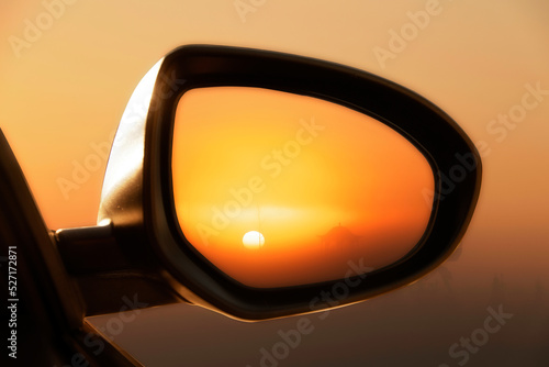 Driving at sunset peek into a rear view mirror close up