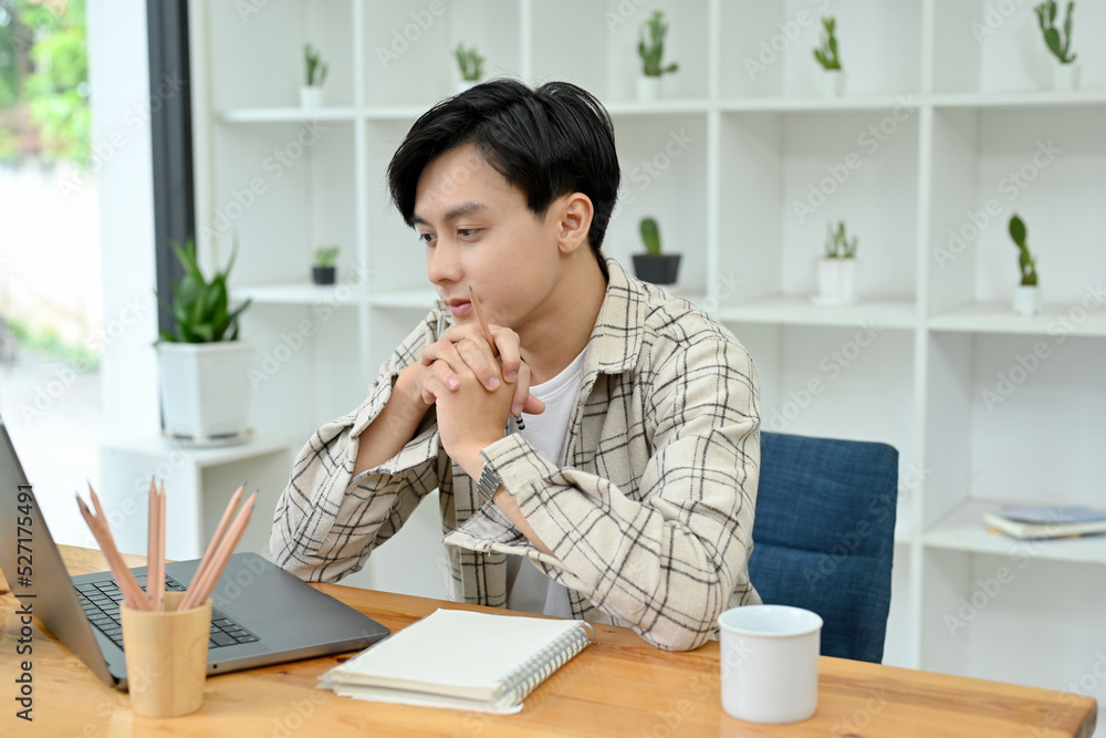Thoughtful Asian man office worker working on his project on notebook laptop Thoughtful Asian man office worker working on his project on notebook laptop