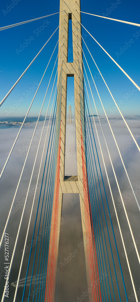 A flight over the pylon of the Russian Bridge built over the Eastern Bosphorus Strait in the East Sea in the capital of the Russian Far East. View from a drone at dawn. Vladivostok cityscape