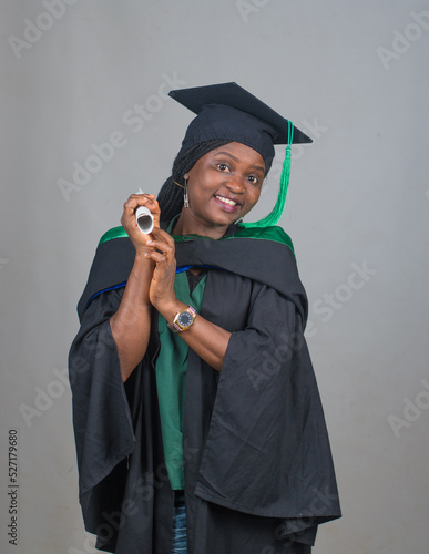 Dancing portrait of an African female student or graduand from Nigeria, wearing graduation gown and cap while posing for the camera and celebrating success in education photo